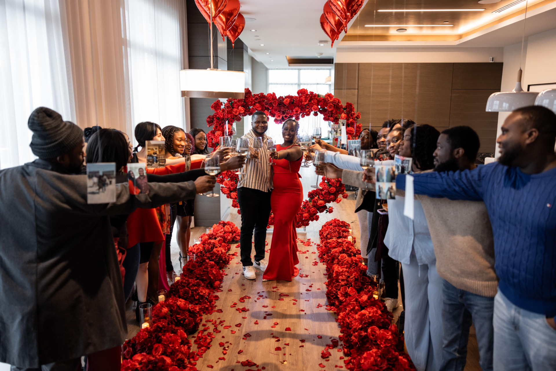 Guests toasting through a red rose heart arch proposal