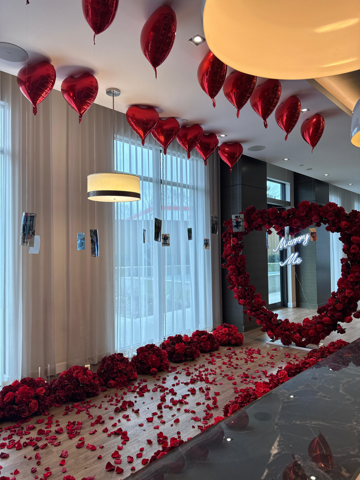 Red heart balloon ceiling above a rose petal aisle and floral heart arch